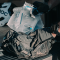 Person holding a HydraPak 1.5 litre Contour Hydration Pack with a helmet and backpack in the background