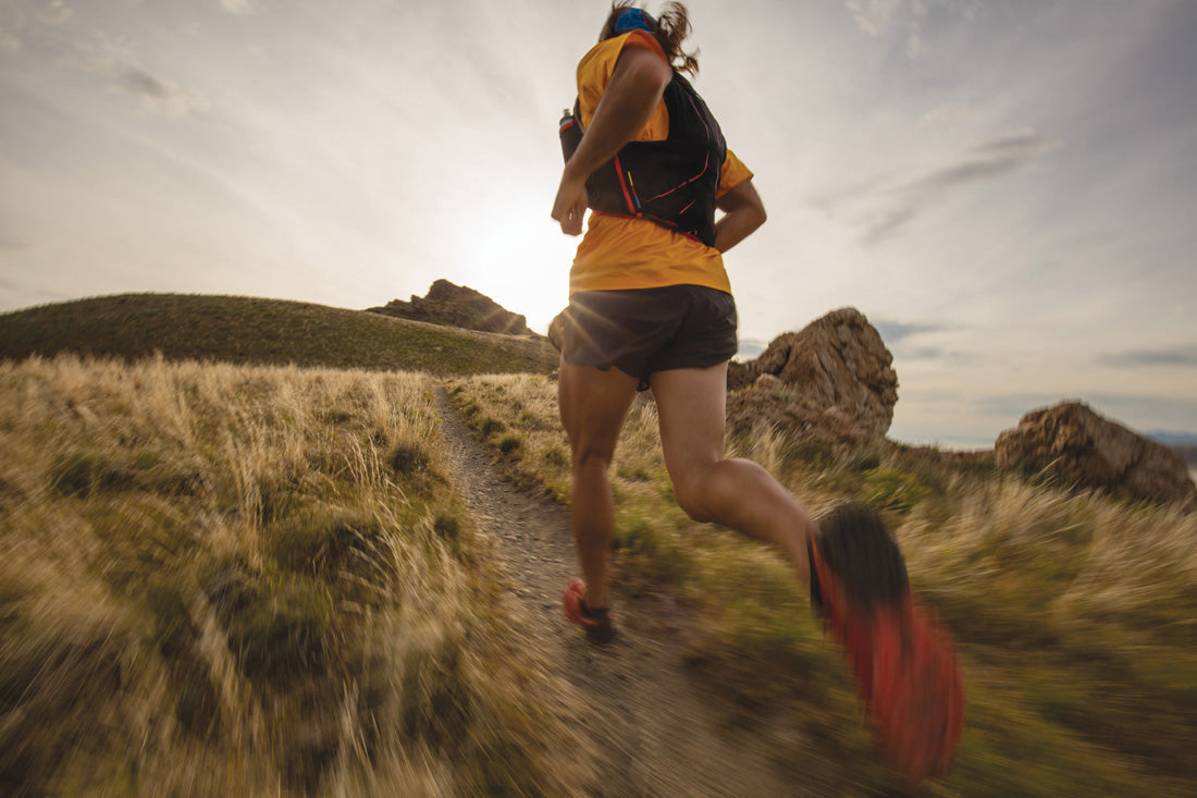 Trail runner heading off into the sunset wearing a hydration vest with HydraPak soft flasks in it