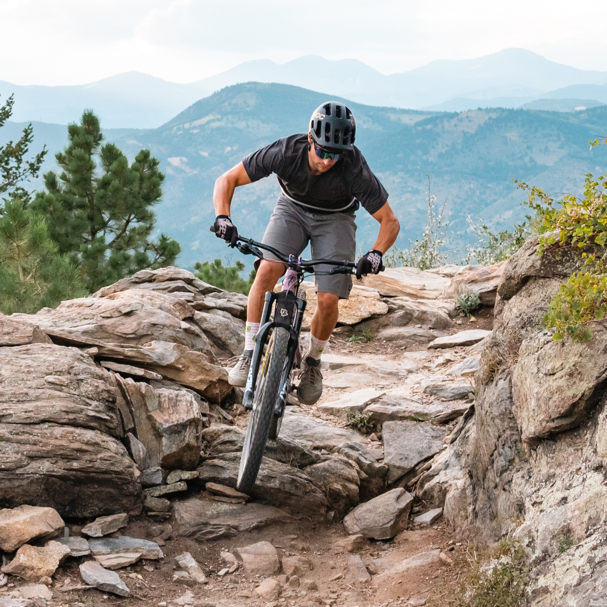 Person mountain biking on a rocky trail with mountains in the background