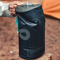 Hand holding the top of a black HydraPak 8 litre expedition water storage bladder with flexible handle